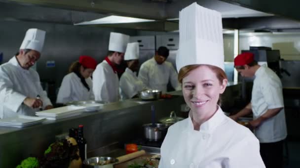 Portret van glimlachen chef-kok en haar personeel in een commerciële keuken — Stockvideo