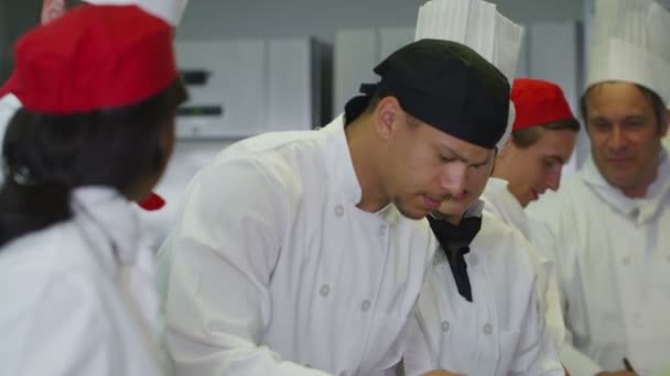 Joyeuse équipe de chefs dans une cuisine commerciale, chef de cuisine goûte et approuve — 图库视频影像