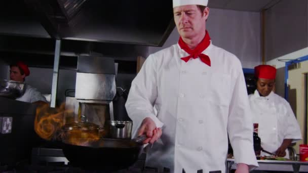 Professional chef in a commercial kitchen cooking flambe style. — Stock Video