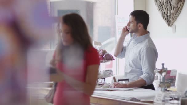 Propietario de la tienda hace llamada telefónica en el trabajo — Vídeos de Stock