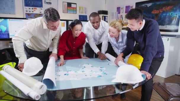 Alegre equipo étnico mixto de arquitectos o ingenieros mirando el mapa del mundo — Vídeos de Stock