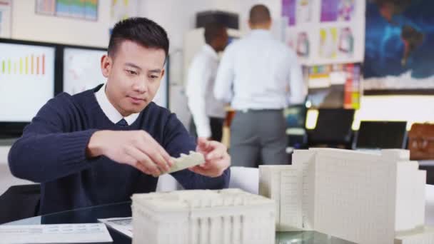 Junger asiatischer Architekt oder Ingenieur betrachtet Konzeptmodelle für neue Entwicklungen — Stockvideo