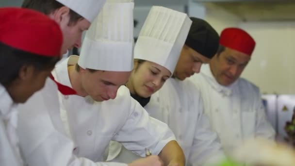 Equipe de chefs profissionais trabalhando juntos em uma cozinha comercial — Vídeo de Stock