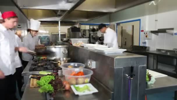 Equipo ocupado de chefs preparando comida en una cocina comercial — Vídeos de Stock