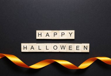 Cadılar Bayramı 'nın en üst manzarası ahşap harflerle ve siyah arkaplan üzerinde lüks turuncu kurdelelerle yatıyordu.