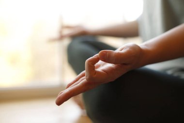 Meditasyon sırasında pencerenin kenarında oturan bir kadının elinin yakın çekimi. Ruh sağlığı konsepti