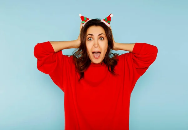 クリスマスの小さな赤い帽子を身に着けている若いアメリカの女性は 恥と驚きの顔 怒りと不満でショックを受け 頭の上に手で強調した 恐怖と過ちへの動揺 — ストック写真