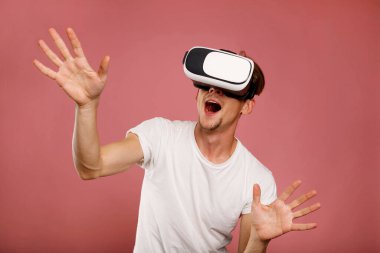 Pembe arka planda sanal gerçeklik gözlüğü takan genç adam. 3B sanal yaşam tarzı kavramı