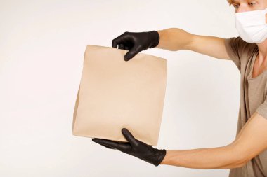 Karton kutular taşıyan bir teslimatçı. Siyah lastik eldivenler ve maske. Hızlı ve ücretsiz teslimat. İnternetten alışveriş ve ekspres teslimat. Karantina konsepti