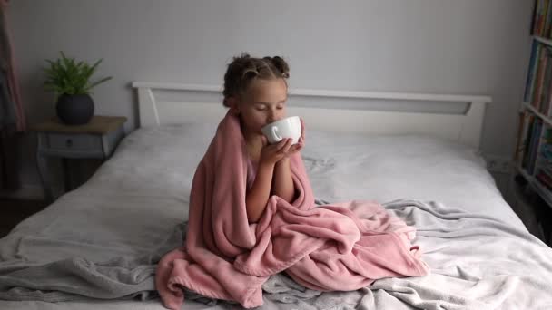 Liten Flicka Som Sitter Sängen Och Dricker För Att Värma — Stockvideo