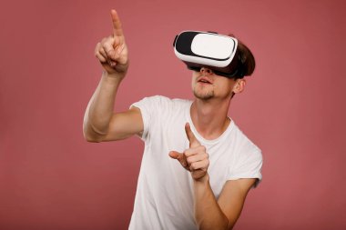 Pembe arka planda sanal gerçeklik gözlüğü takan genç adam. 3B sanal yaşam tarzı kavramı