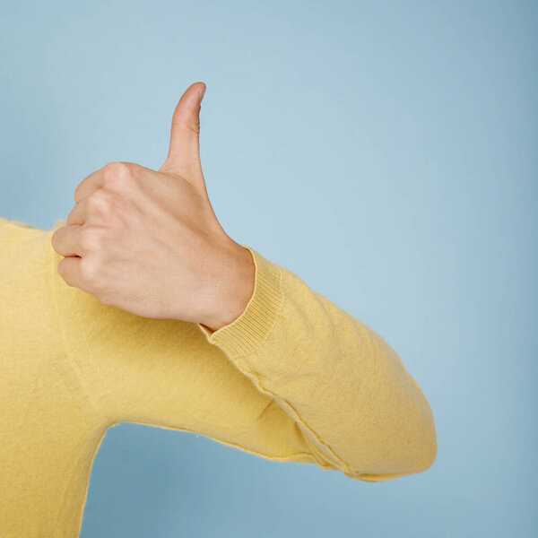 Thump up hand sign isolated on blue background. Copy space for your text