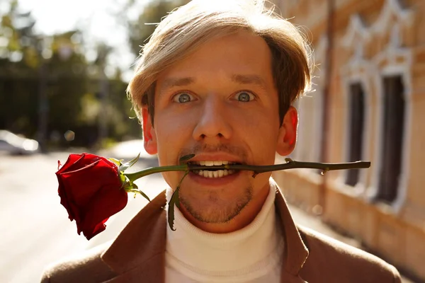 Boldog Jóképű Férfi Mosolyog Miközben Szájában Tartja Vörös Rózsát Utcán — Stock Fotó