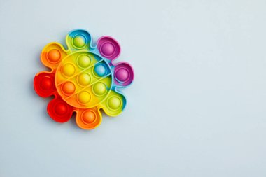 Renkli stres önleyici oyuncağın üst görüntüsü mavi arka planda gökkuşağı çiçeğini ortaya çıkarıyor. Çocuk oyuncaklarının yaratıcı ve komik kavramları. Popüler oyuncak. Moda Oyuncağı 2021-2022.
