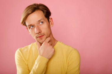 Pembe arka planı düşünen genç bir adamın yakın çekimi.