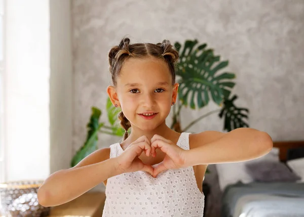 Malá Hezká Holčička Dvěma Culíky Ukazujícími Gesto Srdce Rukama Úsměvy — Stock fotografie