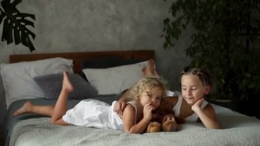 Yatakta dinlenen iki küçük kız kardeş, büyük olan küçüğe sarılıyor. Yatmadan önce aile değerleri ve gelenekleri kavramı