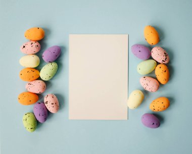 Mutlu Paskalya kompozisyonu, paskalya yumurtaları ve pastel mavi arka planda kağıtlar. Düz konum, üst görünüm, kopyalama alanı