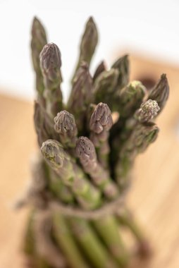 Tahtada bir sürü taze yeşil kuşkonmaz var. İple bağlanmış.