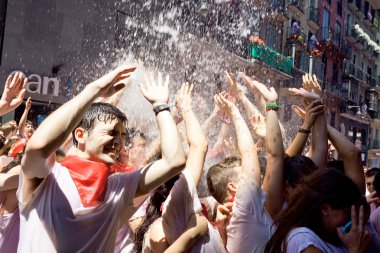 PAMPLONA, SPAIN-JULY 6: People stand under spray of water at ope clipart