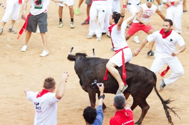 PAMPLONA, SPAIN - JULY 10: People having fun with young bulls at clipart