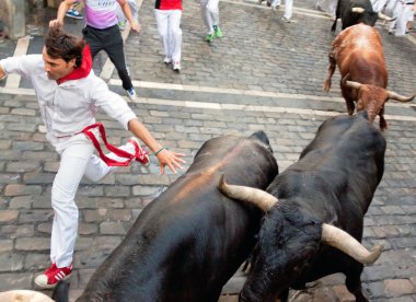 PAMPLONA, SPAIN -JULY 14: Unidentified men run from bulls in str clipart