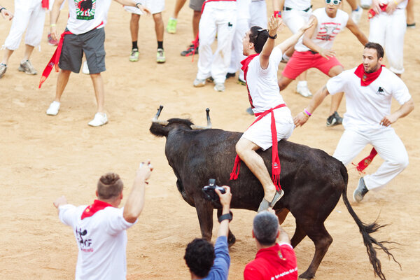 PAMPLONA, SPAIN - JULY 10: People having fun with young bulls at