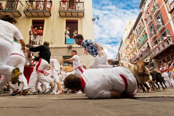 PAMPLONA, SPAIN-JULY 12: People run from bulls on street during — Stock Photo, Image