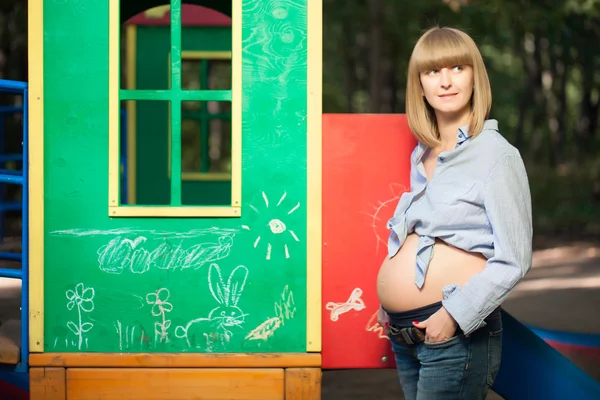 Красивая беременная женщина на детской площадке — стоковое фото