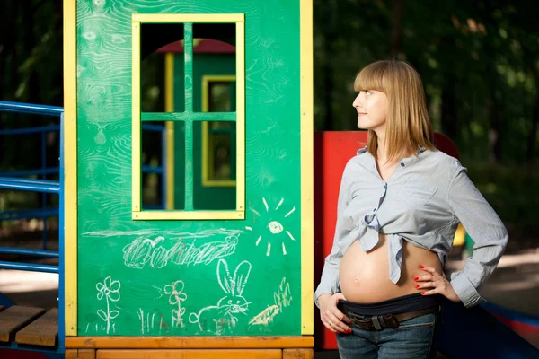 Schöne schwangere Frau auf dem Spielplatz — Stockfoto