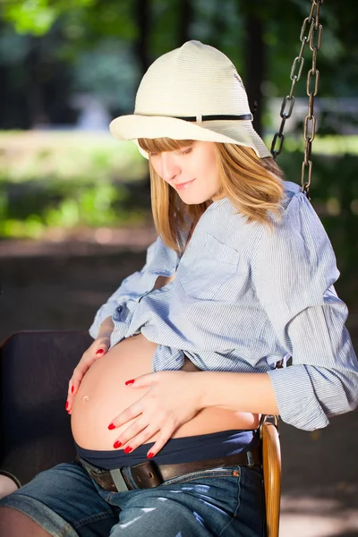 Mujer embarazada hermosa sentada en un columpio — Foto de Stock