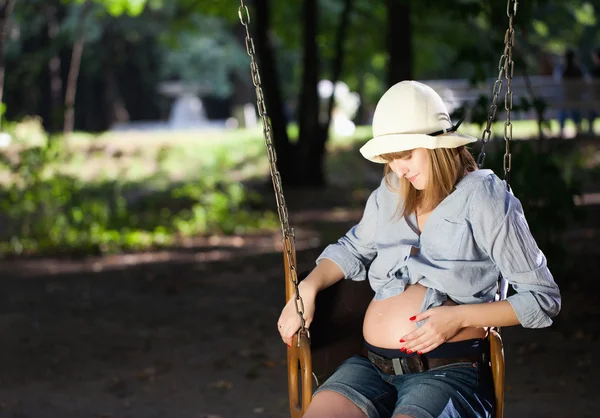 Krásná těhotná žena sedí na houpačce — Stock fotografie