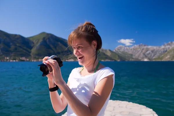 Lächelnde Frau mit Kamera am Strand — Stockfoto