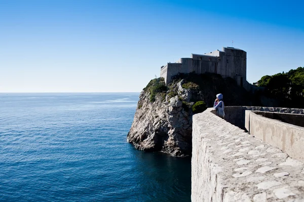 Woman looking over the sea from the city walls — Stock Photo, Image