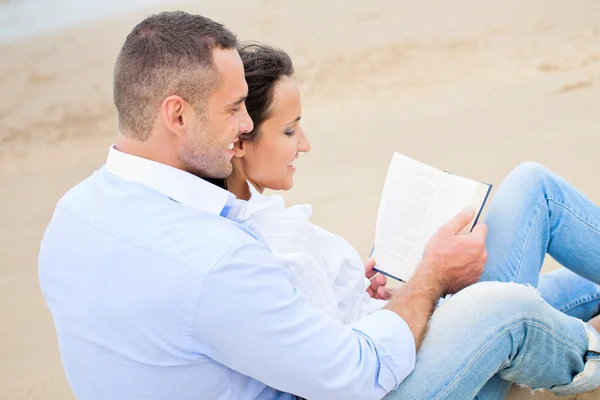 一对夫妇在海滩上看书 — 图库照片