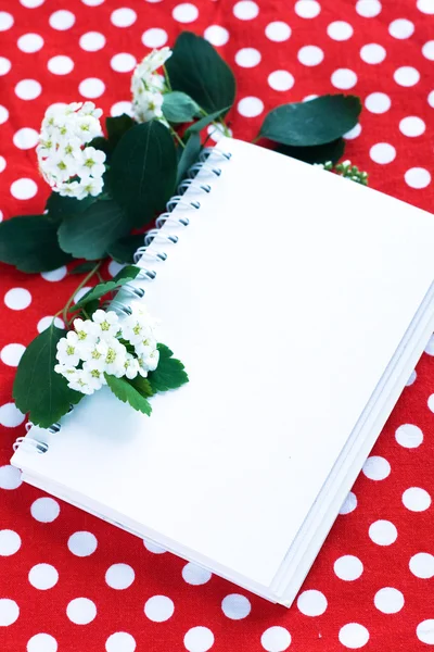 Cuaderno para notas y una rama con flores blancas — Foto de Stock