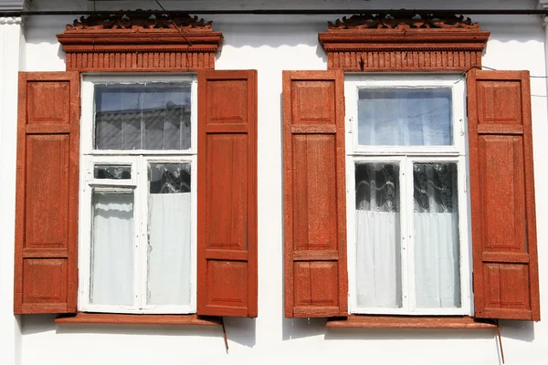 Två gamla fönster med röda träluckor — Stockfoto