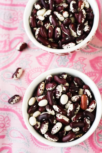 Two bowls with red and white beans on pink tablecloth — Stock Photo, Image