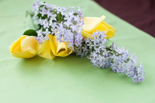 Bouquet of spring flowers lying on a green tablecloth — Stock Photo, Image