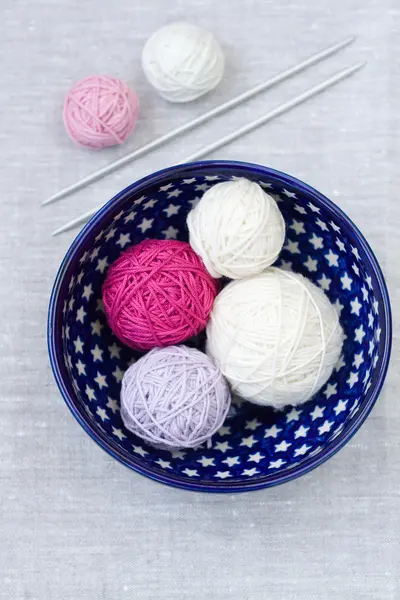 Bolas brillantes de hilo y agujas de tejer en un plato — Foto de Stock