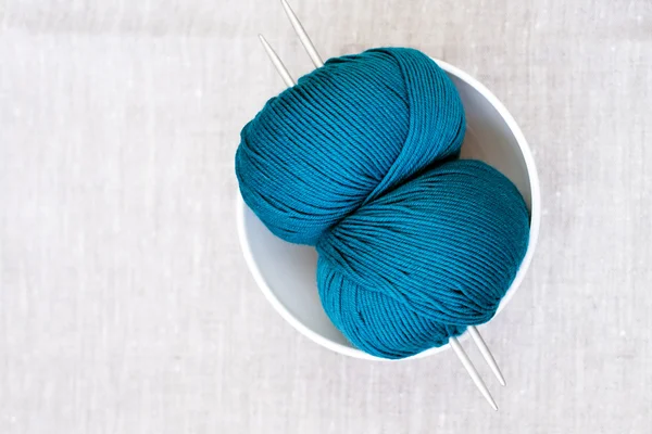 Two bright turquoise skeins of thread and needles for knitting — Stock Photo, Image