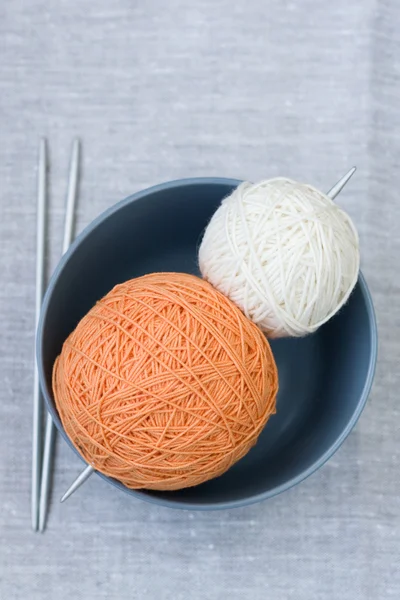 Оранжевые и белые шарики из пряжи и вязальных спиц — стоковое фото