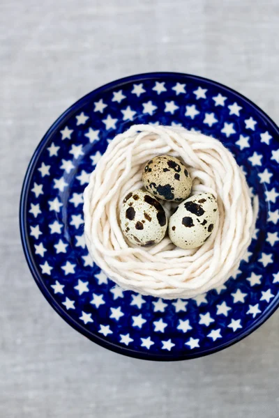 Trois œufs de caille dans le nid avec le fil sur l'assiette — Photo