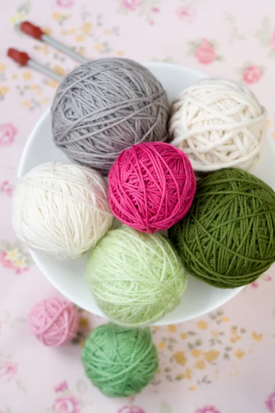 A lot of bright balls of knitting on the background of a pink flower — Stock Photo, Image