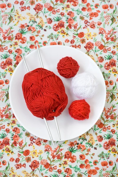 Assiette blanche, les rayons, boule rouge et blanche sur le fond d'une fleur rouge — Photo