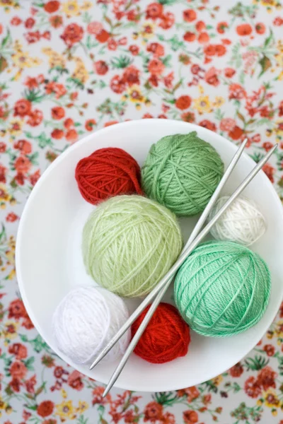A lot of bright balls of knitting on the background of a red flower — Stock Photo, Image