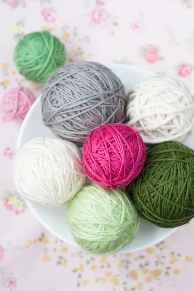 A lot of bright balls of knitting on the background of a pink flower — Stock Photo, Image