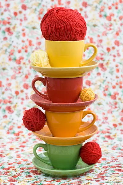 4 つのカラフルなカップと赤い花の背景に糸のボール — ストック写真