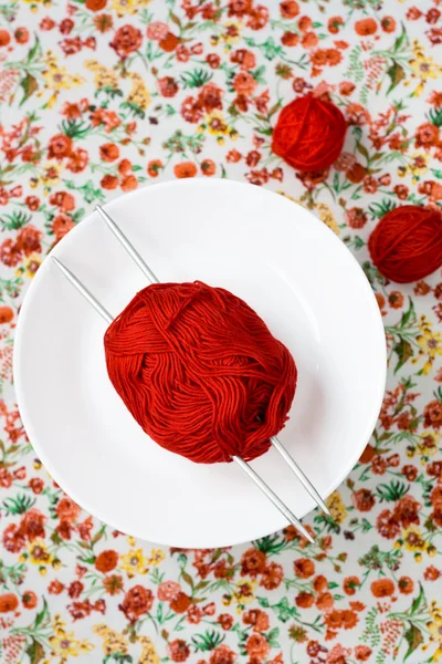 Assiette blanche, les rayons, boule rouge et blanche sur le fond d'une fleur rouge — Photo