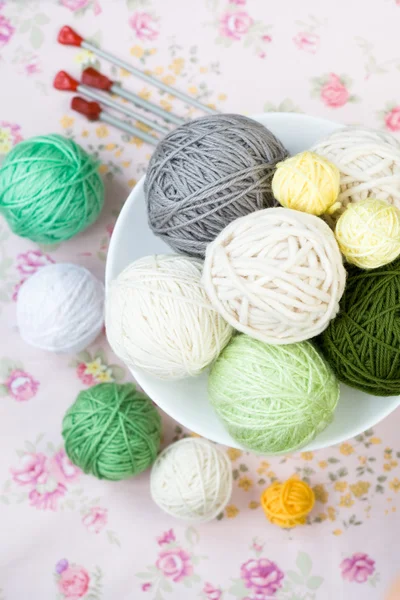 A lot of bright balls of knitting on the background of a pink flower — Stock Photo, Image